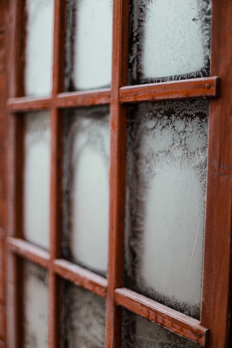 Close-up view of a frosted wooden window, showcasing intricate winter patterns.
